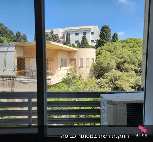 מזגן על אדן חלון עם נוף לעצים ובניינים